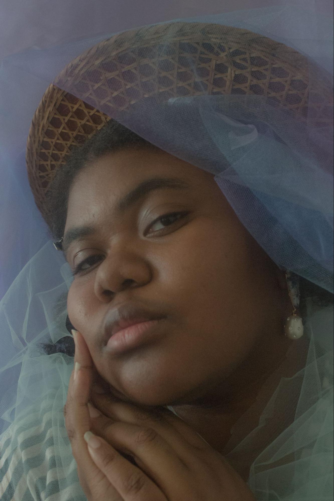 Headshot of woman with dark skin wearing a hat